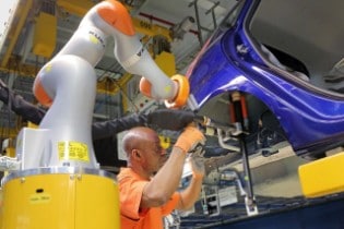Car Workers and Mini Robots Work Hand in Hand 